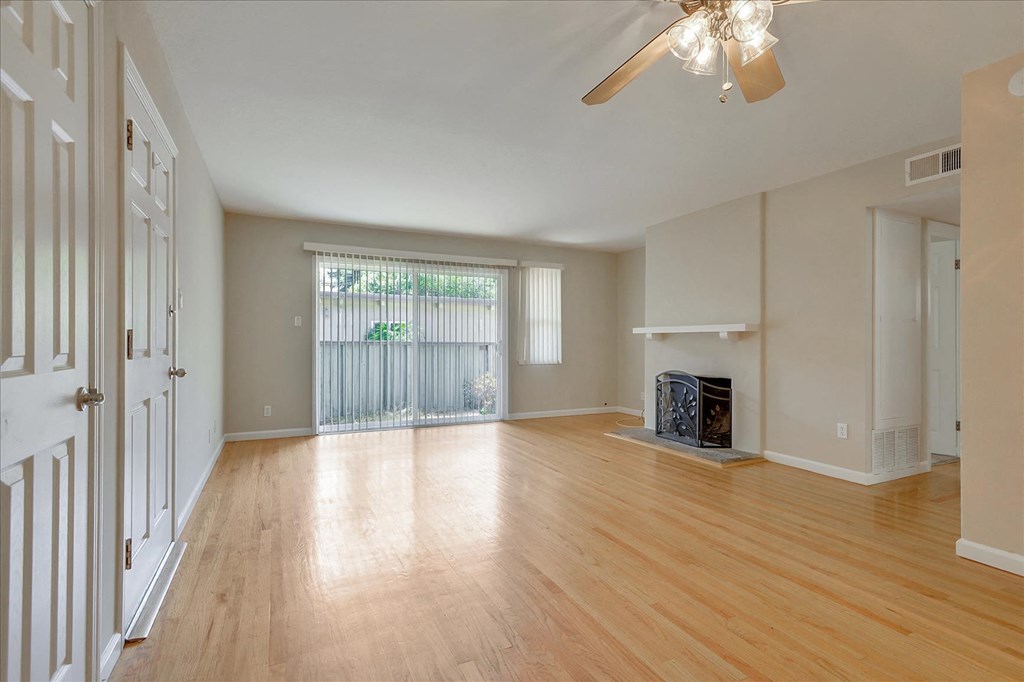 an empty living room with wood floors and a ceiling fan