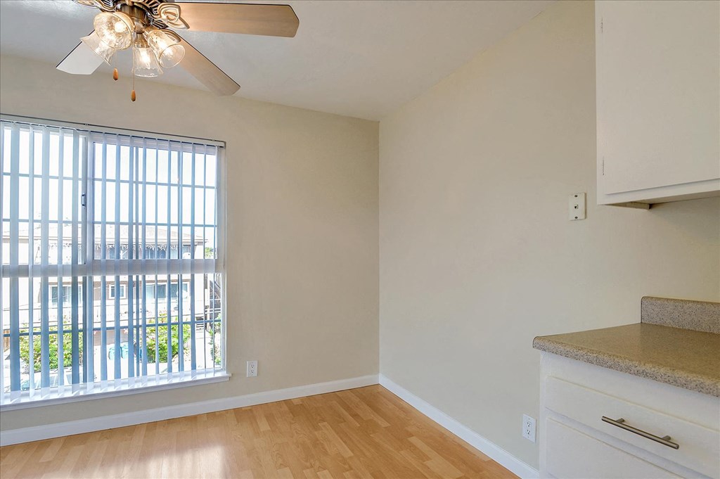 a living room with a large window and a kitchen with wood floors
