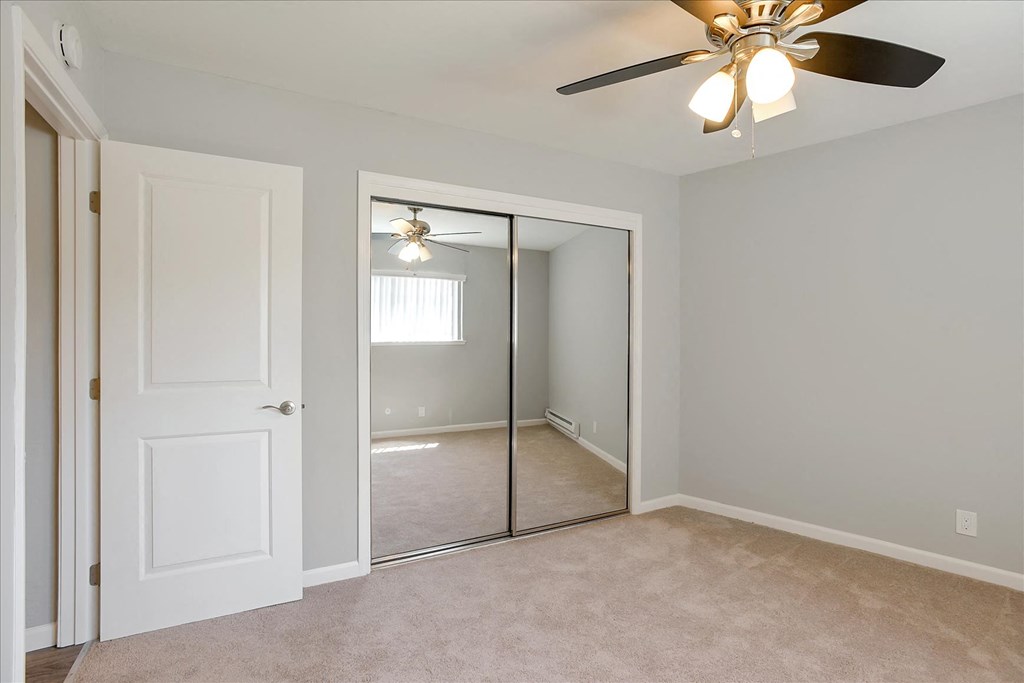 A room with a ceiling fan and a mirror on the wall.