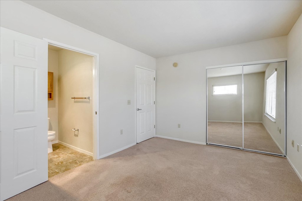 A white room with a carpeted floor and a glass door leading to another room.