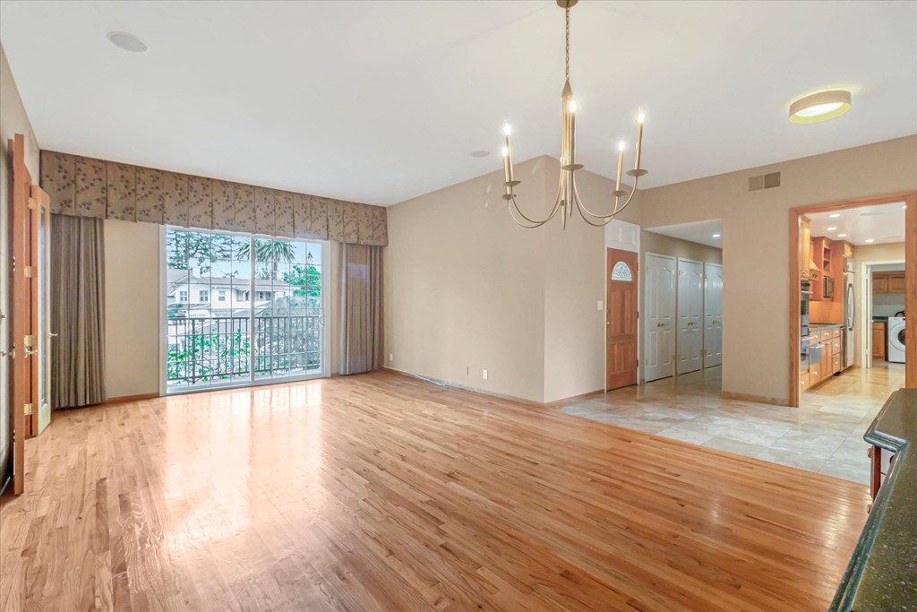 an empty living room with wood floors and a chandelier