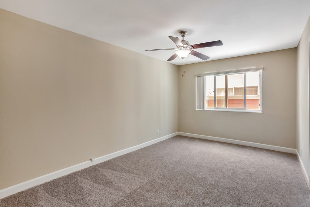 A room with a ceiling fan and a window.