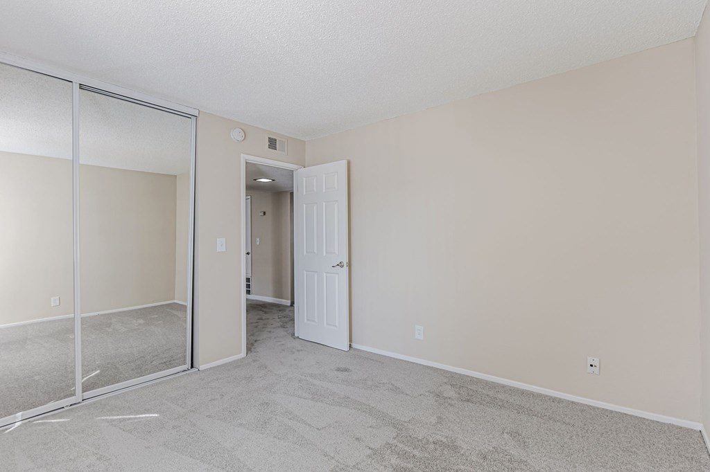 A room with a white door and a carpeted floor.