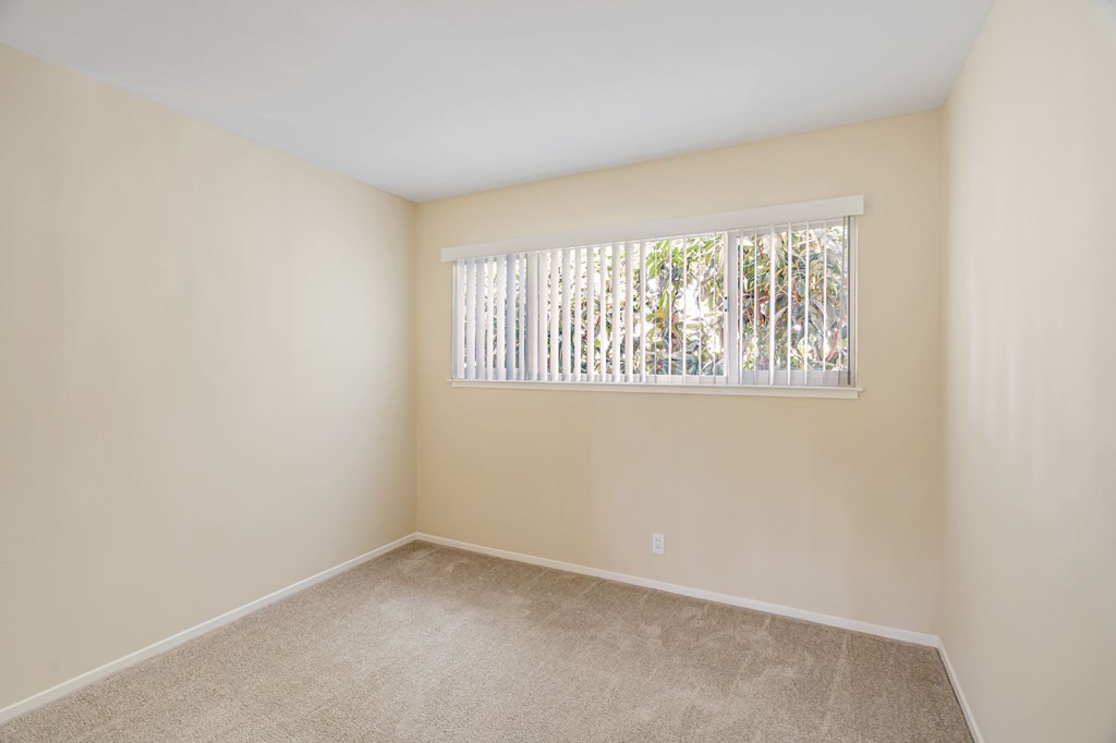 A room with a window covered by white blinds.