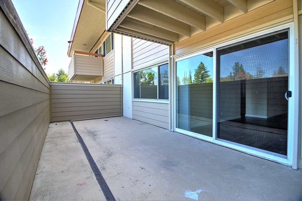 the patio of a home with a large glass sliding door and a patio
