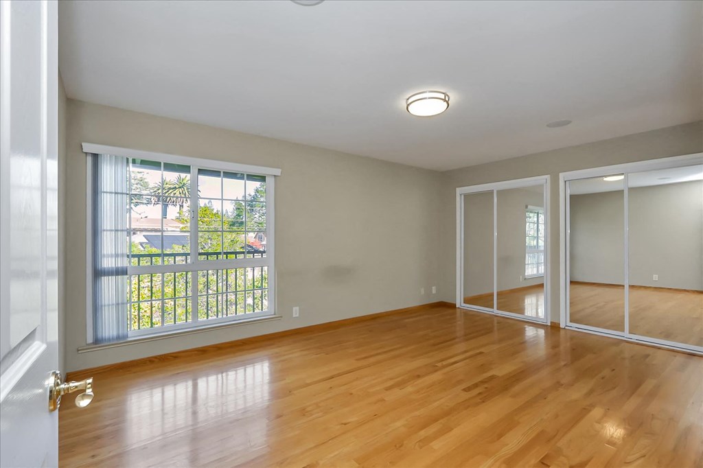 an empty living room with wood floors and a large window