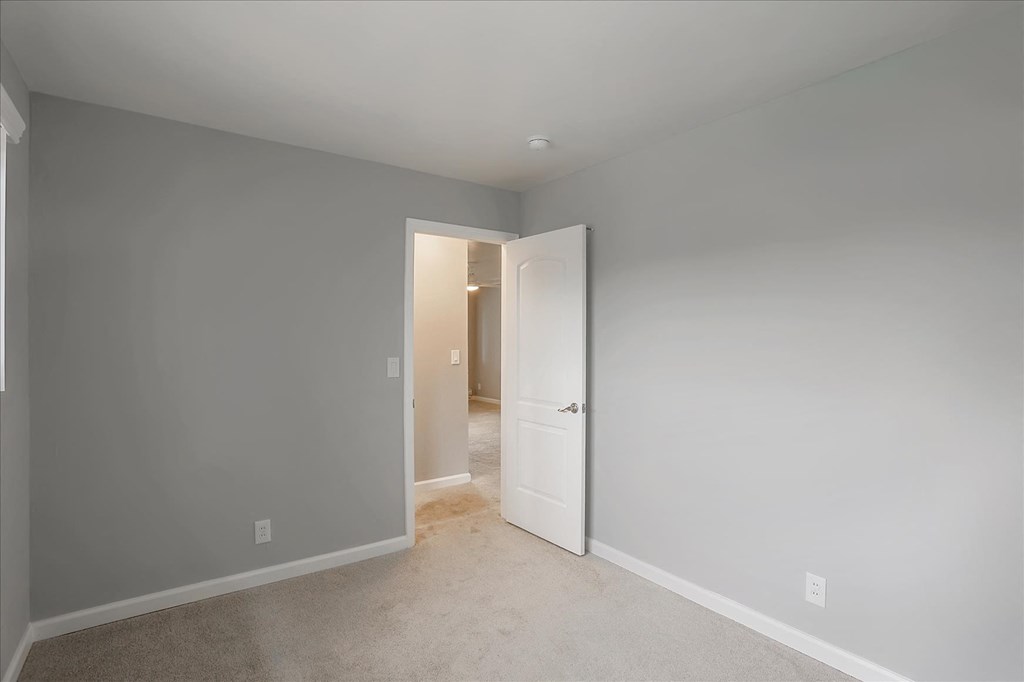 A room with a white door and carpeted floor.