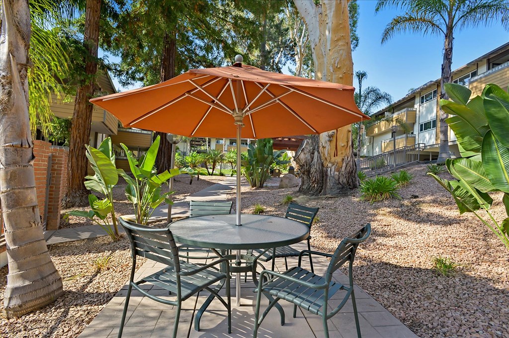 a patio with a table and chairs under an orange umbrella