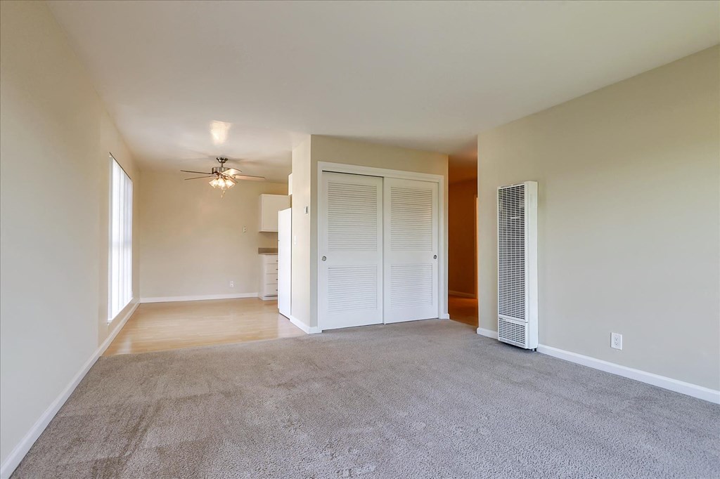 an empty living room with a closet and a ceiling fan