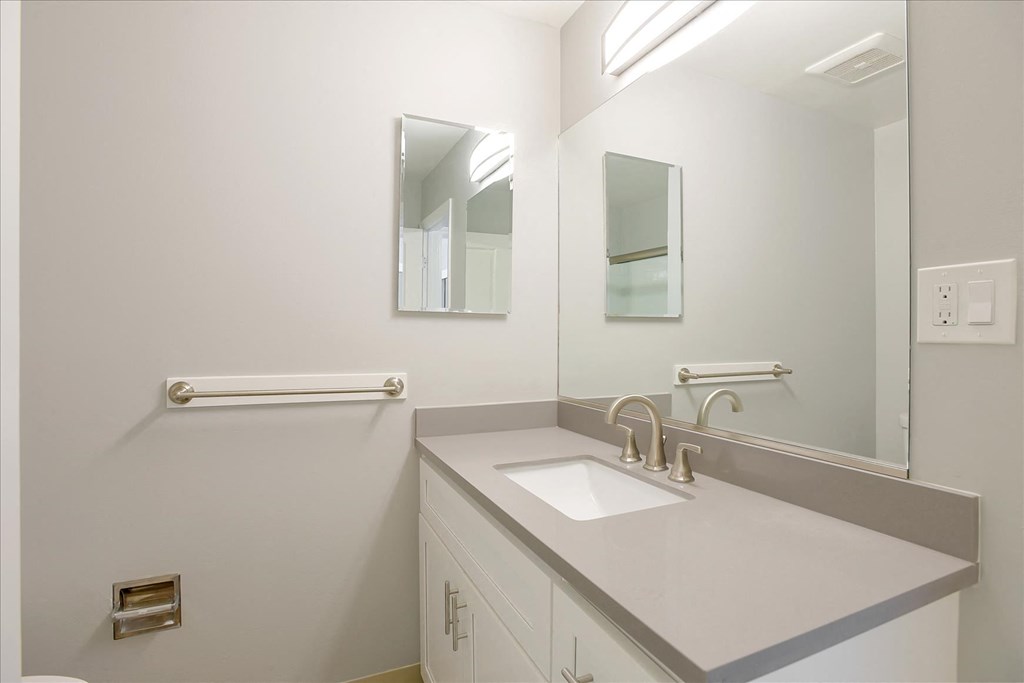 A white sink in a bathroom with a mirror above it.