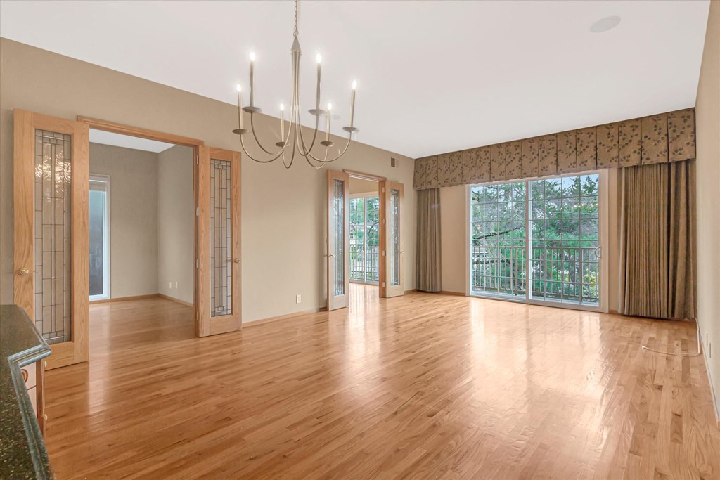 an empty living room with wood floors and a chandelier