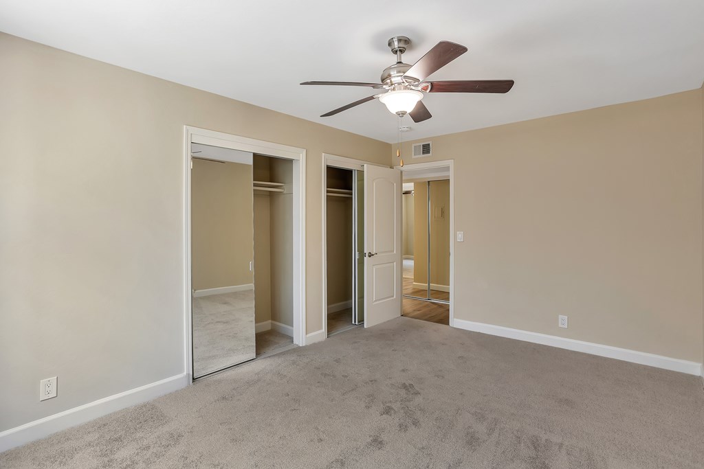 A room with a ceiling fan and carpeted floor.
