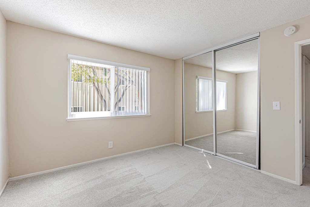 A room with a carpeted floor and a window with blinds.