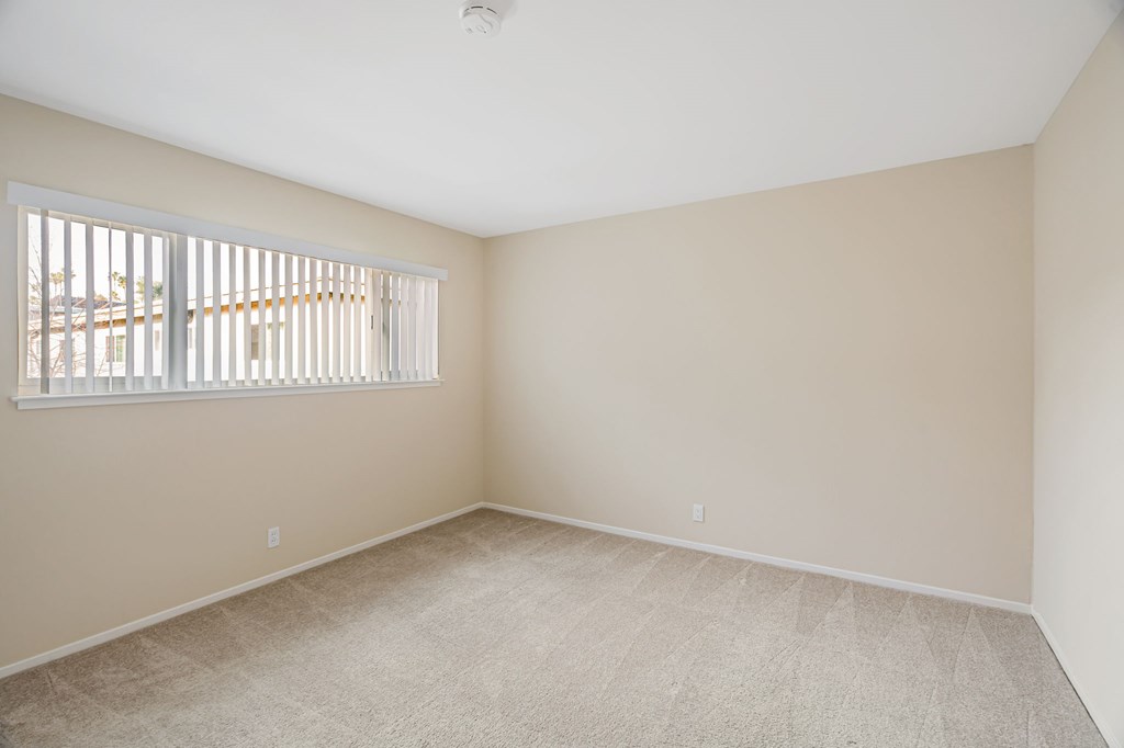 A room with a window and carpeted floor.