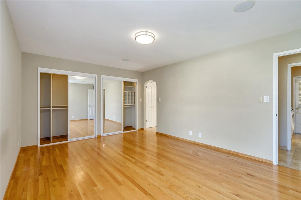 an empty living room with wood floors and a mirrored closet