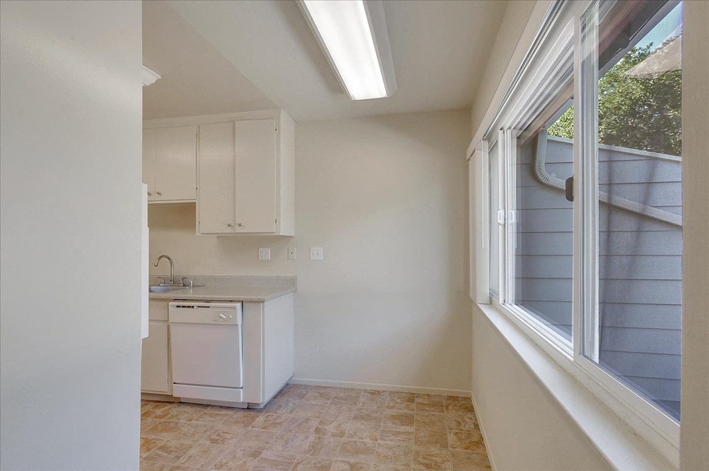 A kitchen with white cabinets and a washing machine.