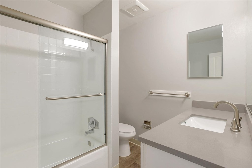 A white bathroom with a glass shower door and a white toilet.