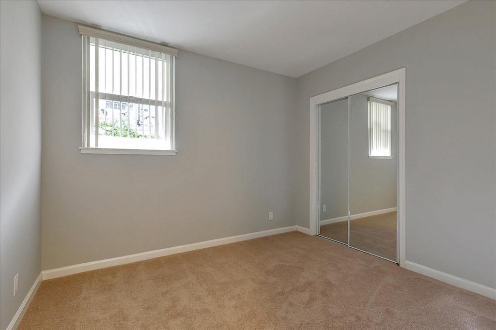 a bedroom with a door to a closet and a window