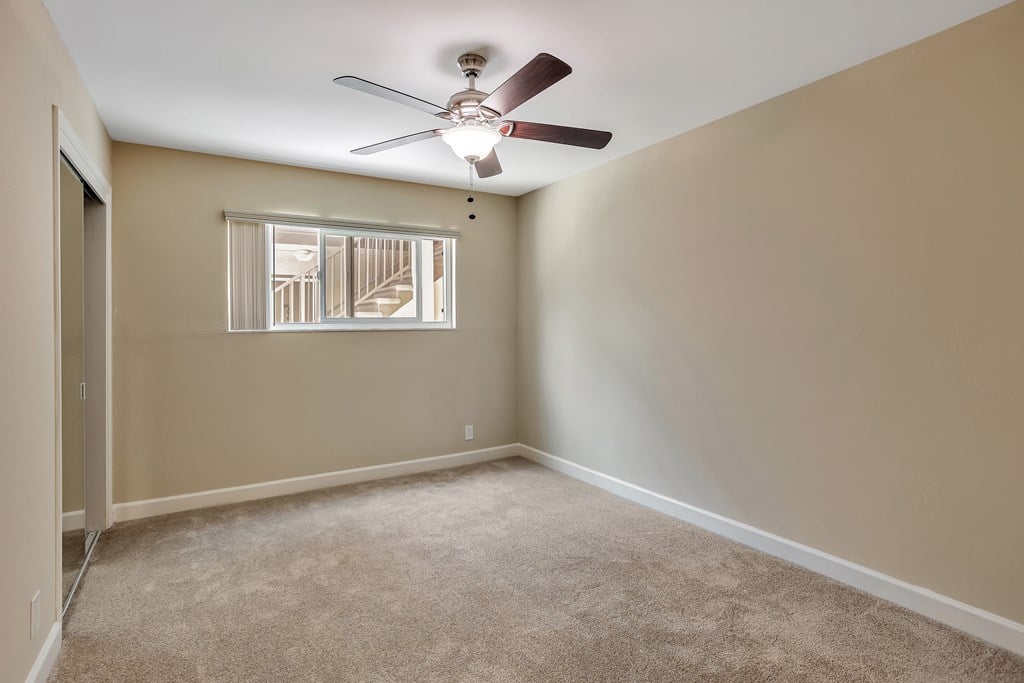 A room with a ceiling fan and carpeted floor.