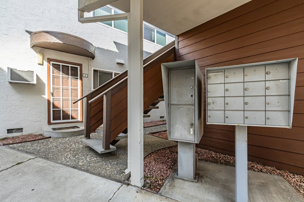 A mailbox is attached to a pole next to a wooden staircase.