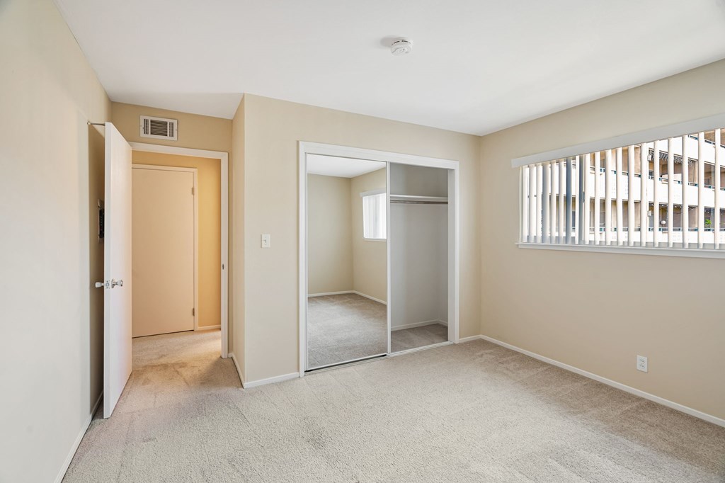 A room with a carpeted floor and a window with blinds.