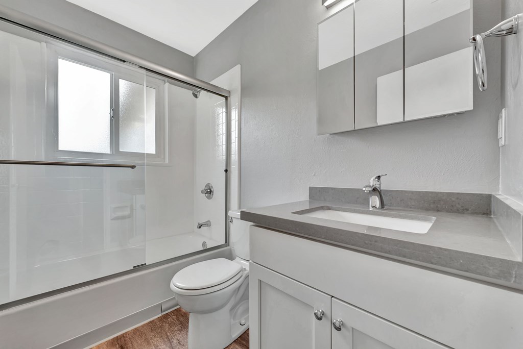 A white bathroom with a toilet, sink, and shower.