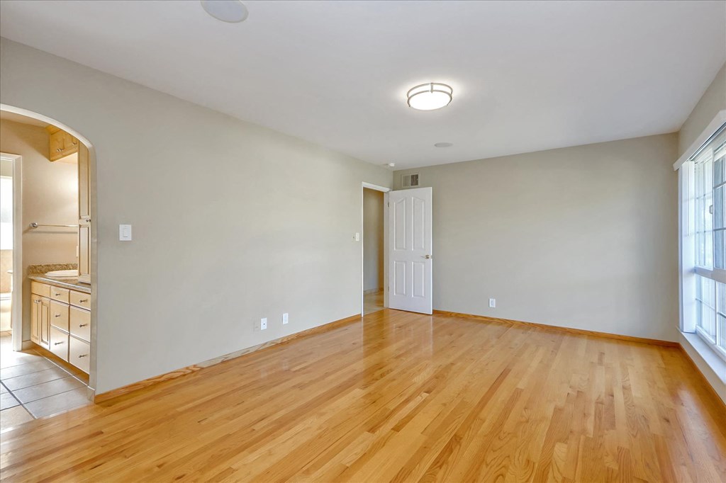 a living room with wood floors and a door to a kitchen