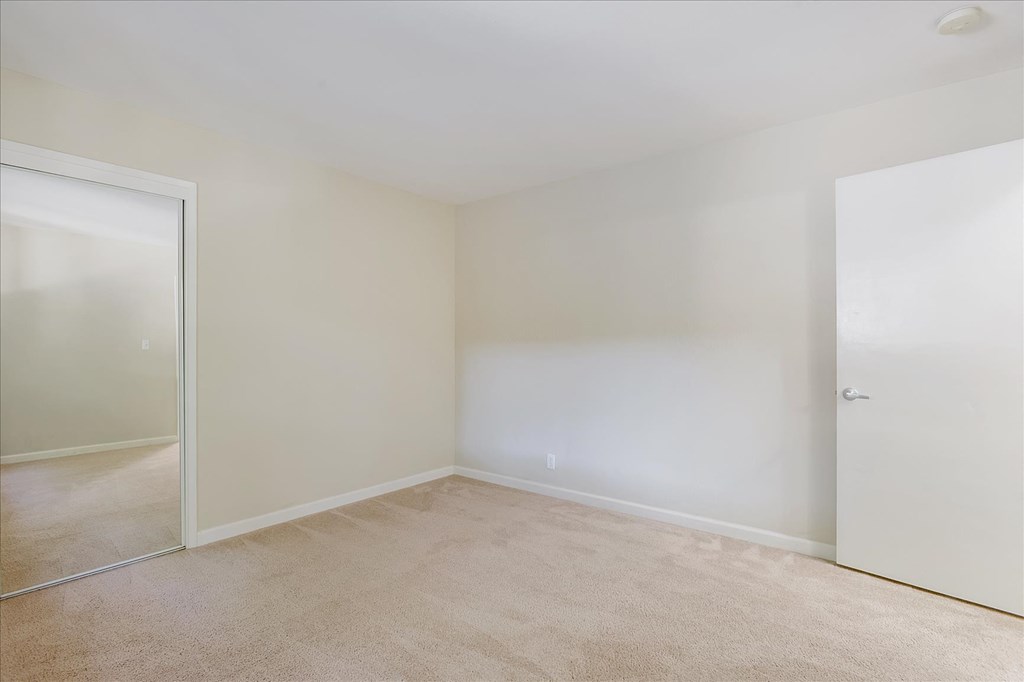 an empty bedroom with a door to a closet