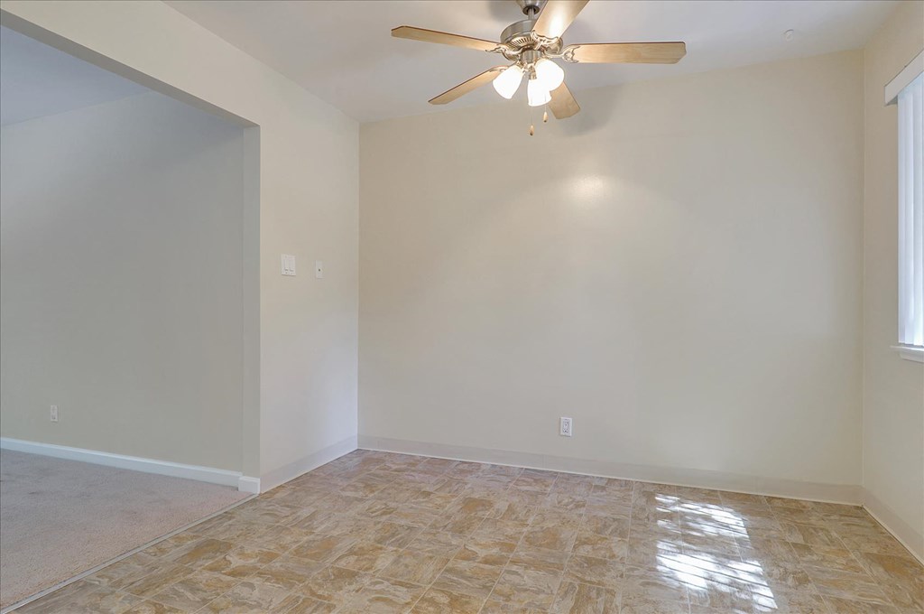 A room with a ceiling fan and tiled floor.