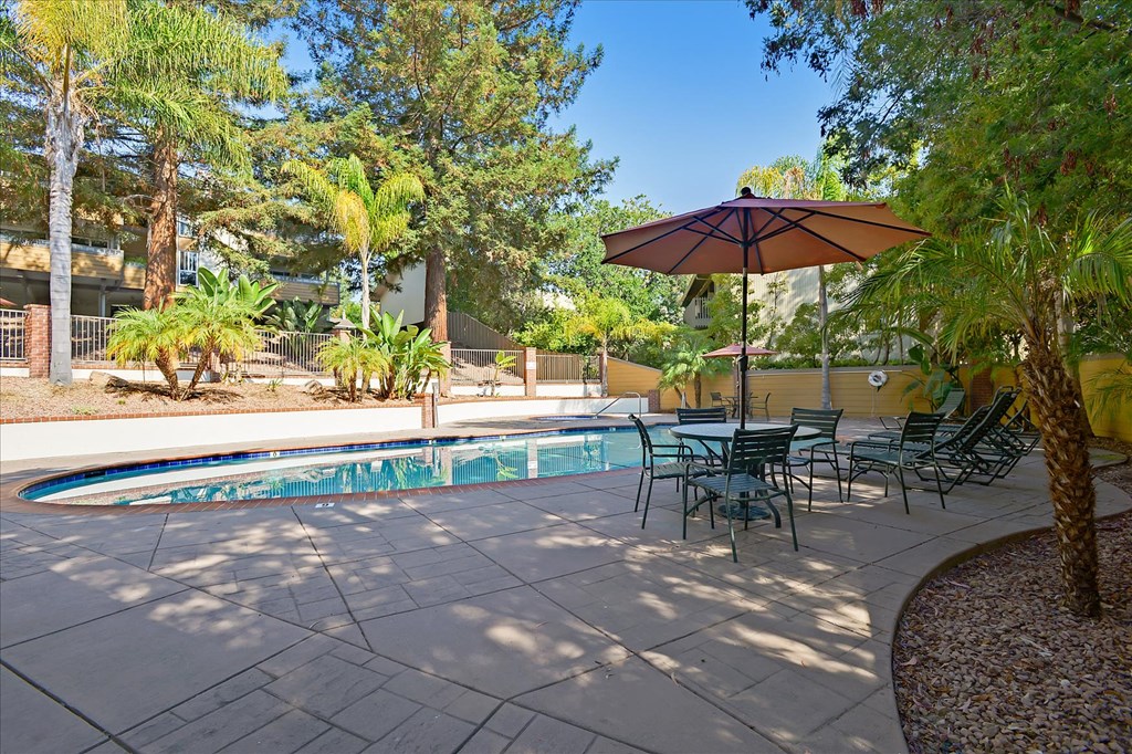 a swimming pool with patio furniture and an umbrella