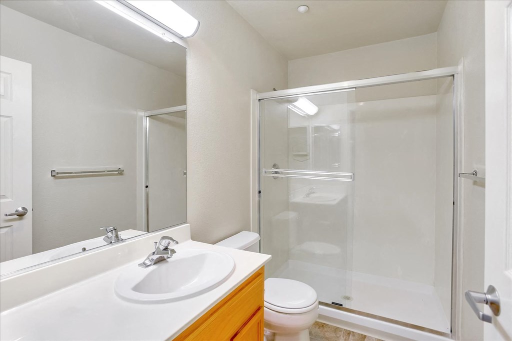 A white sink in a bathroom with a toilet and a glass shower door.