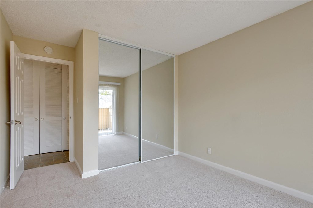 an empty bedroom with mirrored closet doors