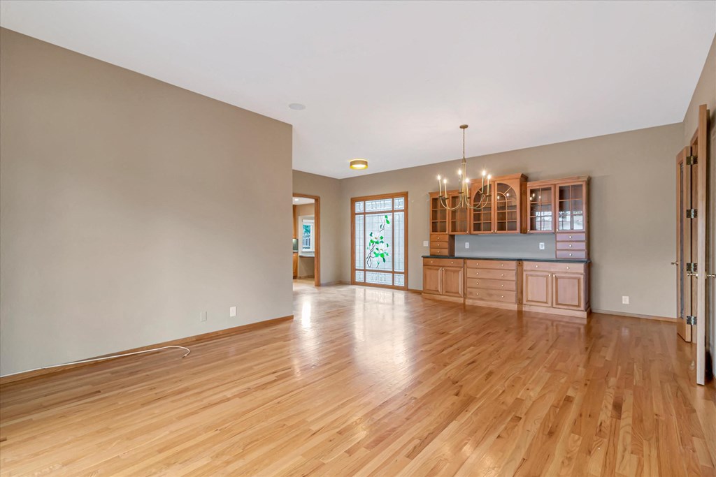 an empty living room and kitchen with wood flooring and a door to a balcony
