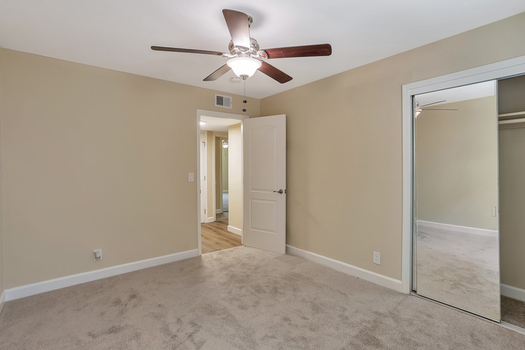 A room with a ceiling fan and a mirror on the wall.