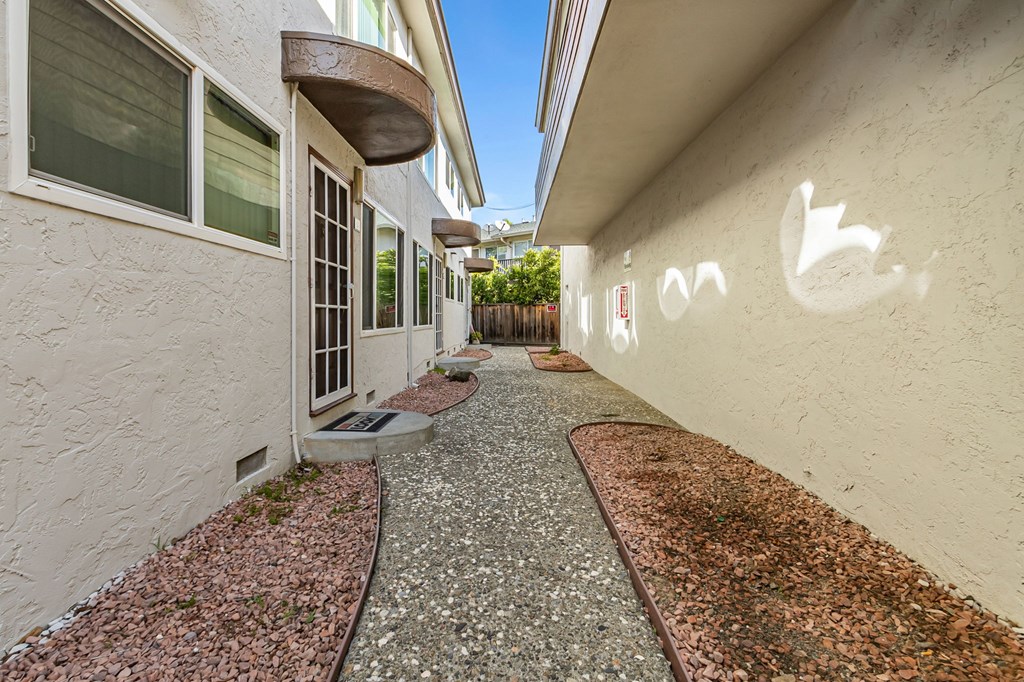 A pathway with gravel and a wall with a white arrow painted on it.