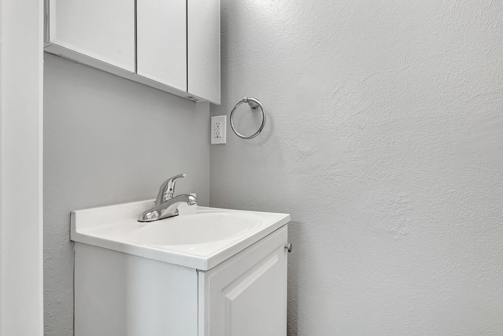 A white sink is mounted under a white cabinet.