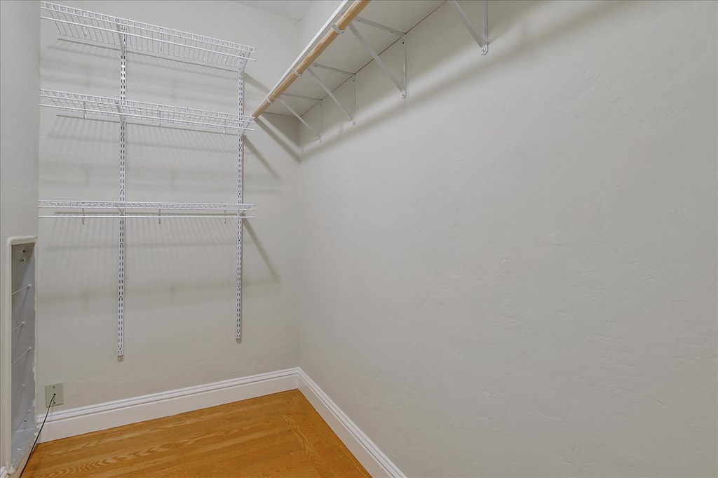 a closet with shelves on the wall and a wood floor