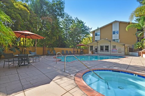 A pool with a hot tub and a building in the background.