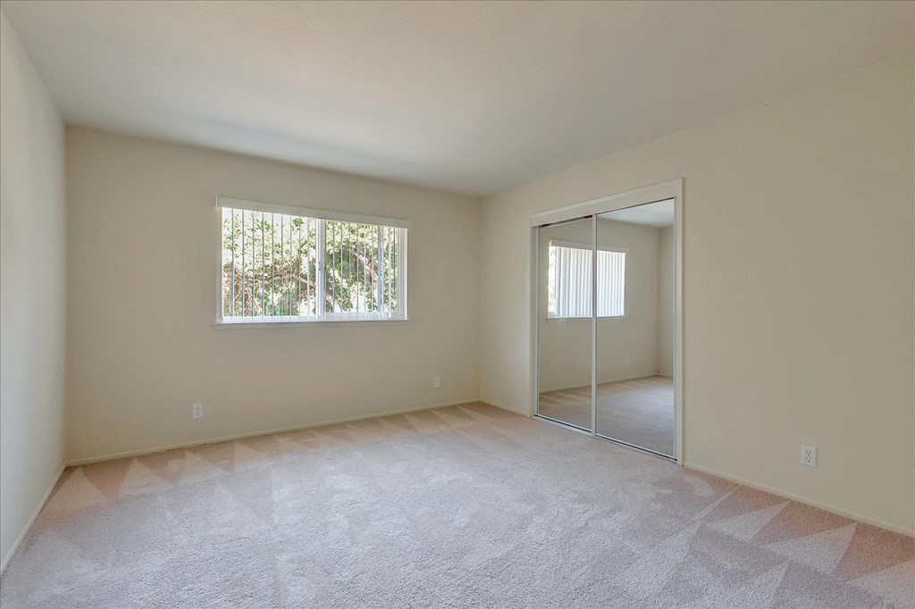 A room with a carpeted floor and a window.