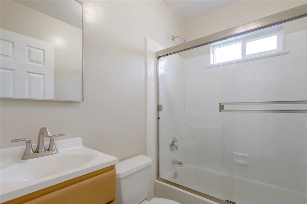A white sink with a silver faucet is in a bathroom with a walk in shower.