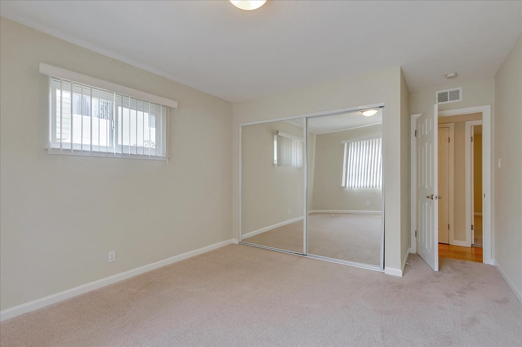 an empty bedroom with a mirrored closet and a door to the bathroom