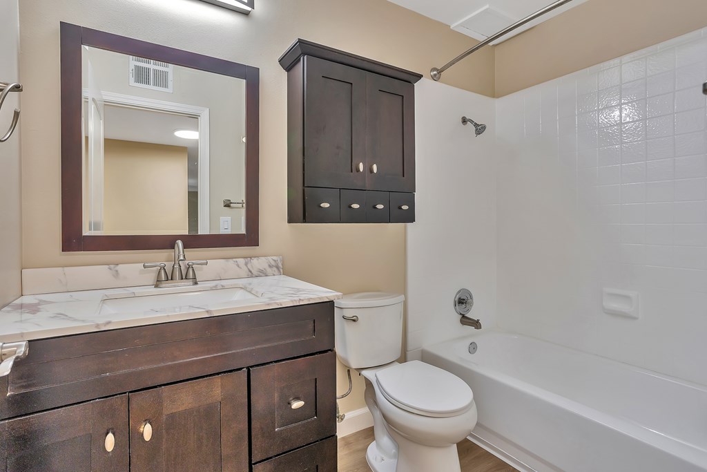 A bathroom with a white toilet and a white bathtub.