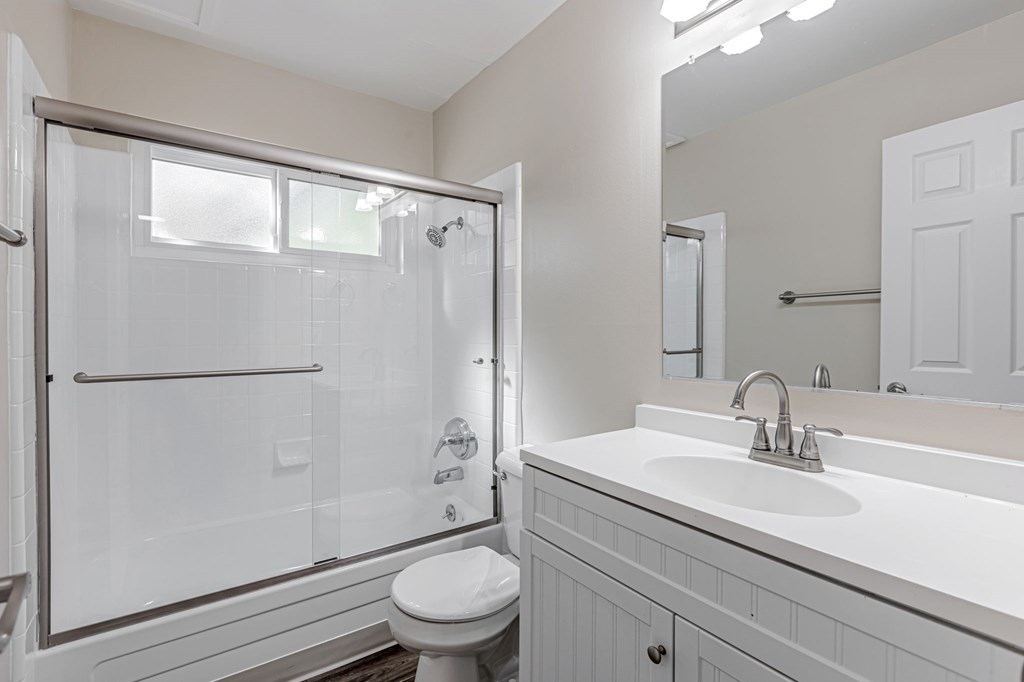 A white bathroom with a toilet, sink, and shower.
