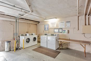 A laundry room with washers and dryers and a bench.