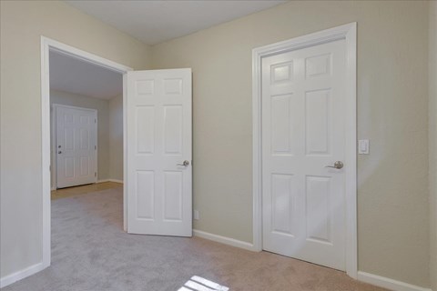 a bedroom with two doors and a door to a closet