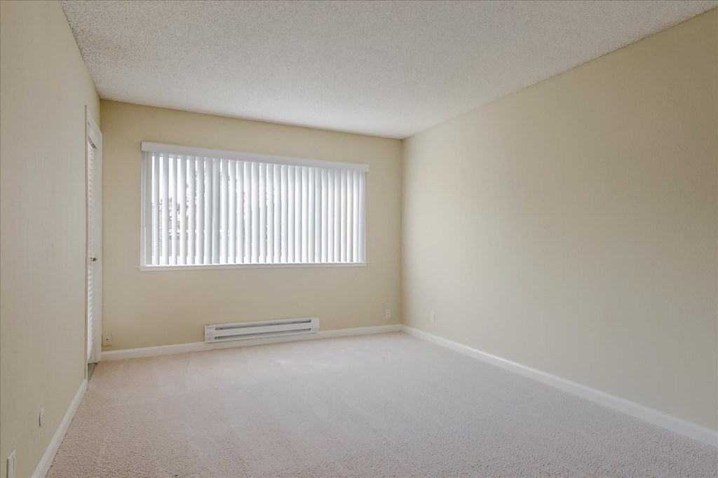 the spacious living room of an empty house with a window