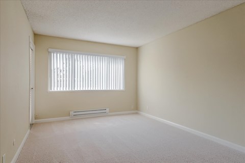 the spacious living room of an empty house with a window