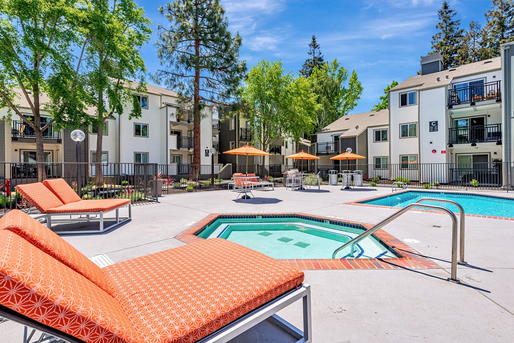 A pool area with orange sun loungers and a small pool.