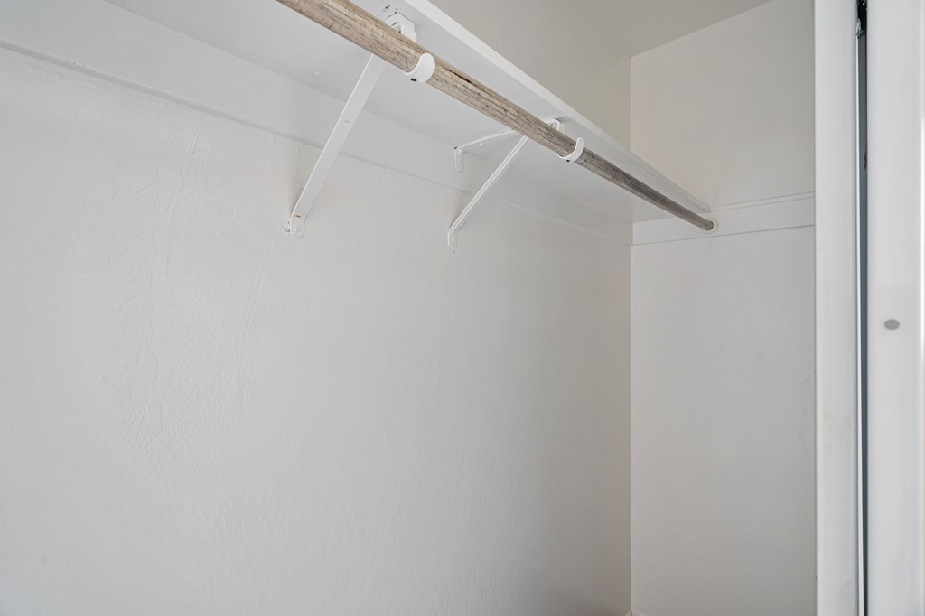 A white wall with a white door and a white shelf.