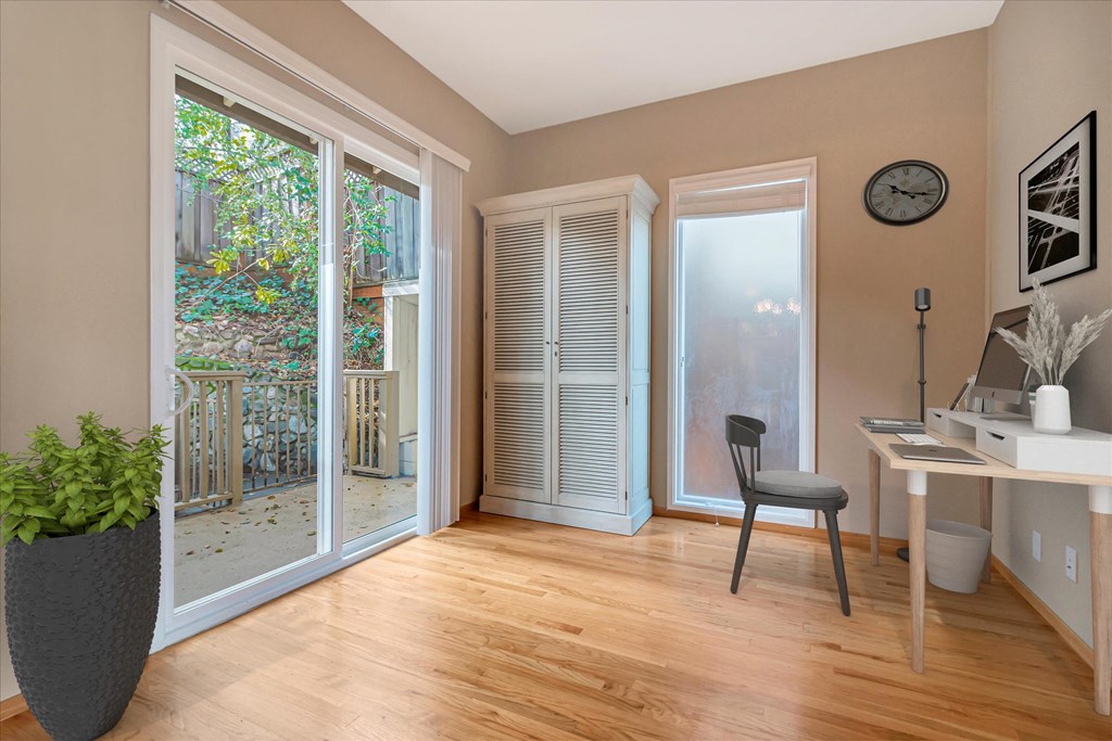 a living room with a desk and a door to a patio